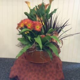 Orange chrysanthemums and calla lilies in a copper-toned container