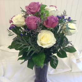 Pink and white roses arranged in a purple vase