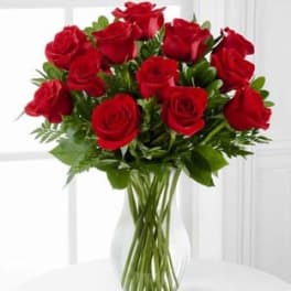 Arrangement of red roses in a clear glass vase on a white table