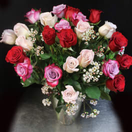Bouquet of red, pink, and white roses in a clear glass vase
