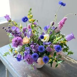 Mixed purple and blue bouquet in a white vase