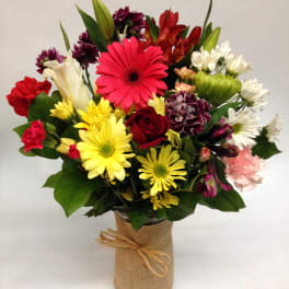 Mixed bouquet of colorful flowers in a burlap-wrapped vase
