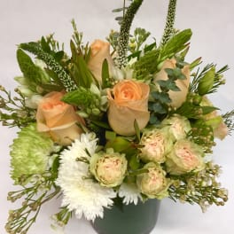 Peach roses and white flowers in a green vase