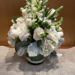 White floral arrangement in a round vase with silvery foliage
