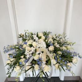 Large white and blue floral spray with ribbon on a stand