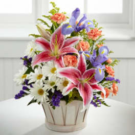 Mixed bouquet of lilies, irises, daisies, and carnations in a white basket