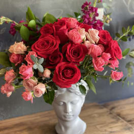 Bouquet of red and pink roses in a white bust vase