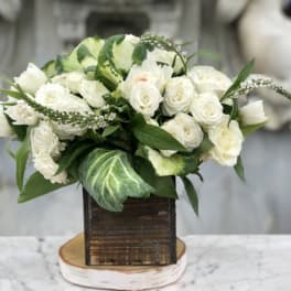 White rose bouquet in a rustic wooden box with green foliage