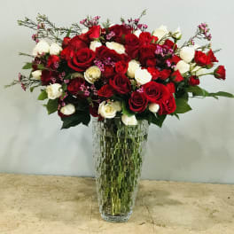 Red and white roses arranged in a tall glass vase