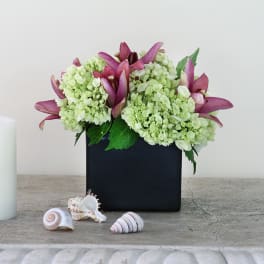 Pink lilies and pale green hydrangeas in a black square vase