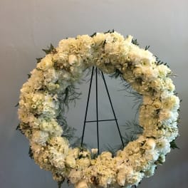 White floral wreath on a black stand
