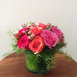 Pink and coral roses arranged in a green glass vase
