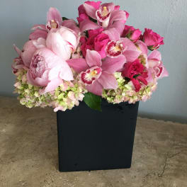 Pink orchid and rose arrangement in a black rectangular vase