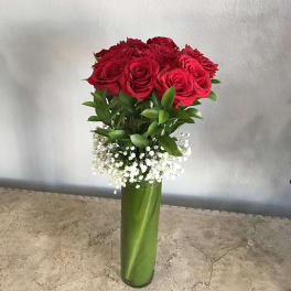 Red roses in a tall green vase with white baby's breath