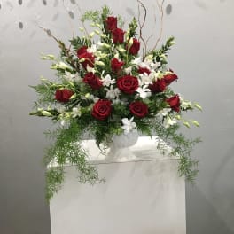 Red roses and white flowers arranged in a white vase