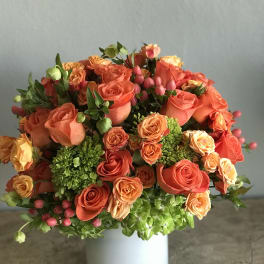 Orange and peach rose bouquet in a white vase