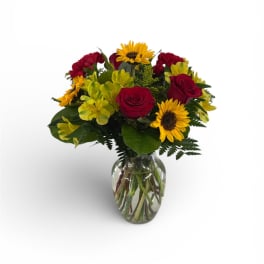 Bouquet of red roses and yellow sunflowers in a glass vase