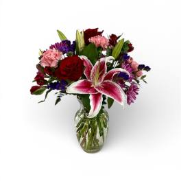 Bouquet of red roses, pink carnations, and a pink lily in a glass vase