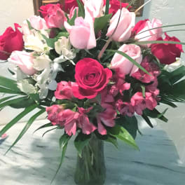 Bouquet of pink and red roses with white flowers in a glass vase