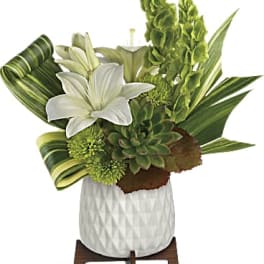 White lilies and green tropical flowers in a white vase