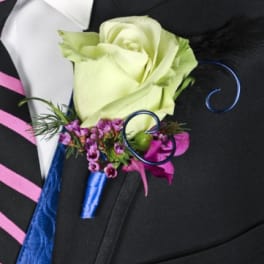 White rose boutonniere with purple accent flowers on a suit lapel