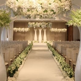 White floral wedding aisle with hanging arrangements and tall pedestal centerpieces