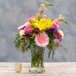 Mixed bouquet in a glass vase with pink, yellow, and purple flowers