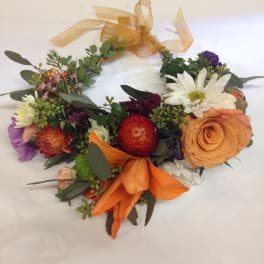 Colorful floral wreath with orange ribbon and mixed blooms