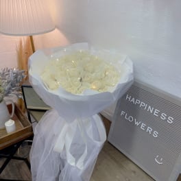 Bouquet of white roses wrapped in sheer tulle with a ribbon