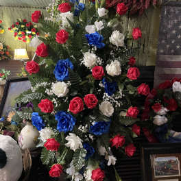 Tall arrangement of red, white, and blue roses with greenery