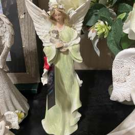A decorative angel figurine in a pale green dress holding a small animal