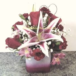 Pink lilies and dark red roses arranged in a square vase