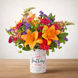 Bright mixed bouquet with orange lilies and pink roses in a birthday vase