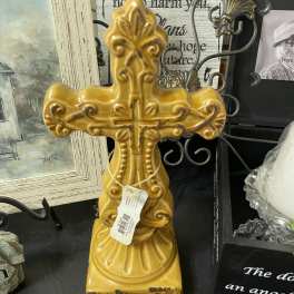 Decorative yellow ceramic cross on a shelf