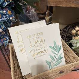 Two decorative canvas signs in a woven basket with gold lettering