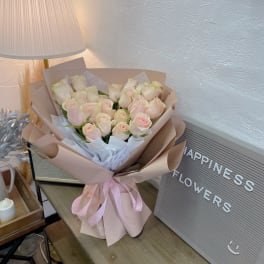 Bouquet of pale pink roses wrapped in blush paper with a pink ribbon