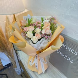 Bouquet of pale pink and white flowers wrapped in peach paper