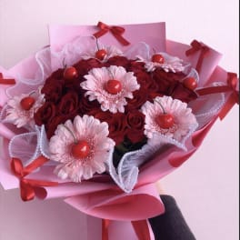 Bouquet of red roses and pale pink daisies with red ribbon accents