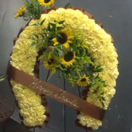 Yellow floral funeral wreath with sunflowers and a brown ribbon on an easel
