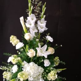 Tall white floral arrangement in a carved stone vase