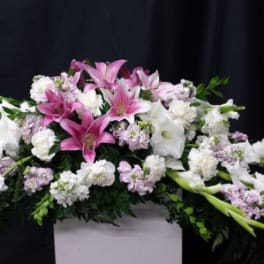 Pink and white lily arrangement with carnations in a white container
