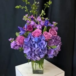 Purple and pink floral arrangement in a clear glass vase