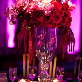 Tall floral centerpiece in a glass vase with red and pink blooms