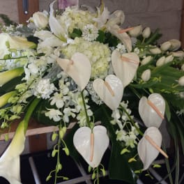 White floral casket spray with calla lilies, orchids, and anthuriums