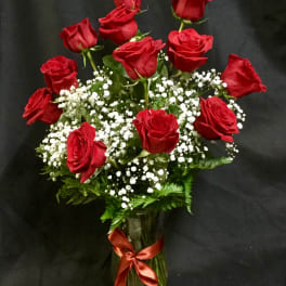 Red roses arranged in a glass vase with white baby's breath