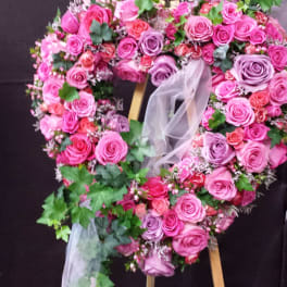 Heart-shaped floral wreath of pink and purple roses on an easel