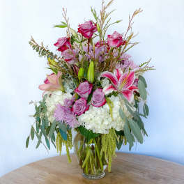 Bouquet of pink roses, lilies, and lavender flowers in a glass vase