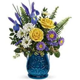 Yellow roses and purple flowers in a blue glass vase