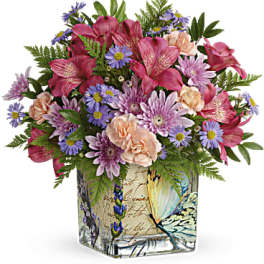 Mixed pink and purple bouquet in a butterfly-patterned square vase