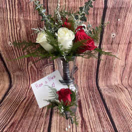 Red and white roses in a clear vase with greenery and a small card